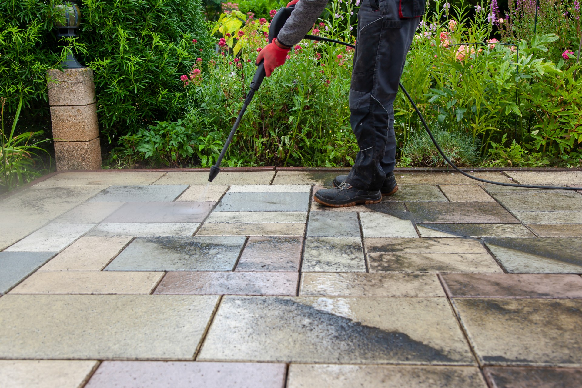 Cleaning stone slabs on patio with the high-pressure cleaner.